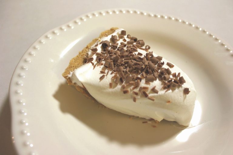 A slice of Hershey Pie: An Easy Chocolate Pie Recipe sitting on a white plate and topped with chocolate shavings.