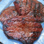 Three cooked steaks with grill marks resting on a blue plate for an easy grilled petite sirloin steak recipe.